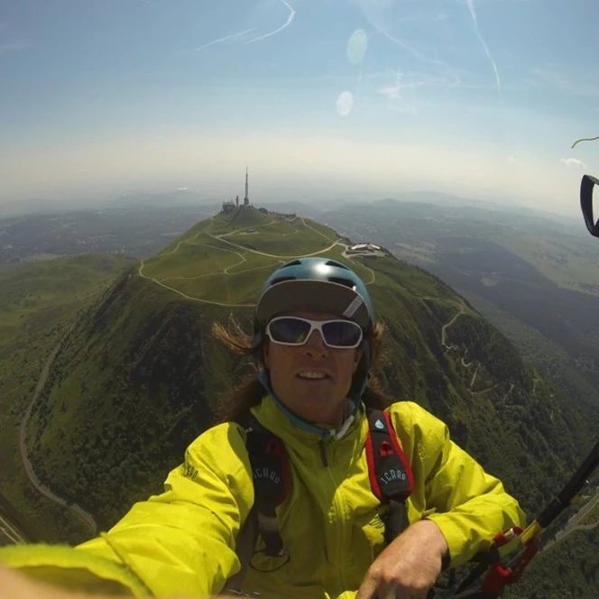 Aidan Davis flying above a mountain ridge in a yellow jacket