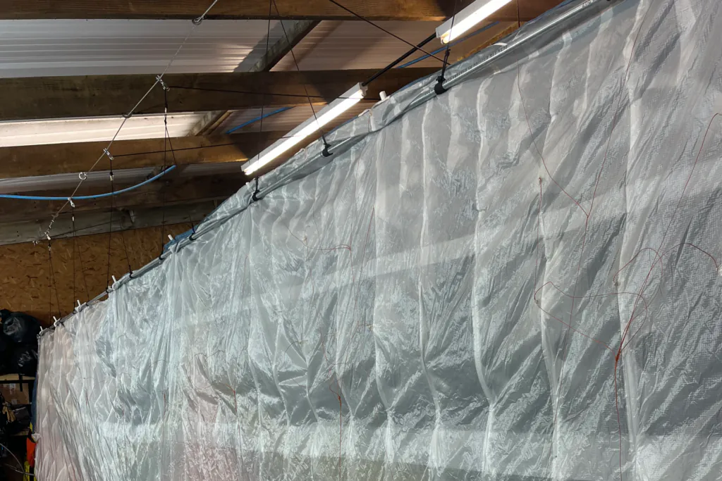 A paraglider wing suspended for a fabric inspection in the workshop