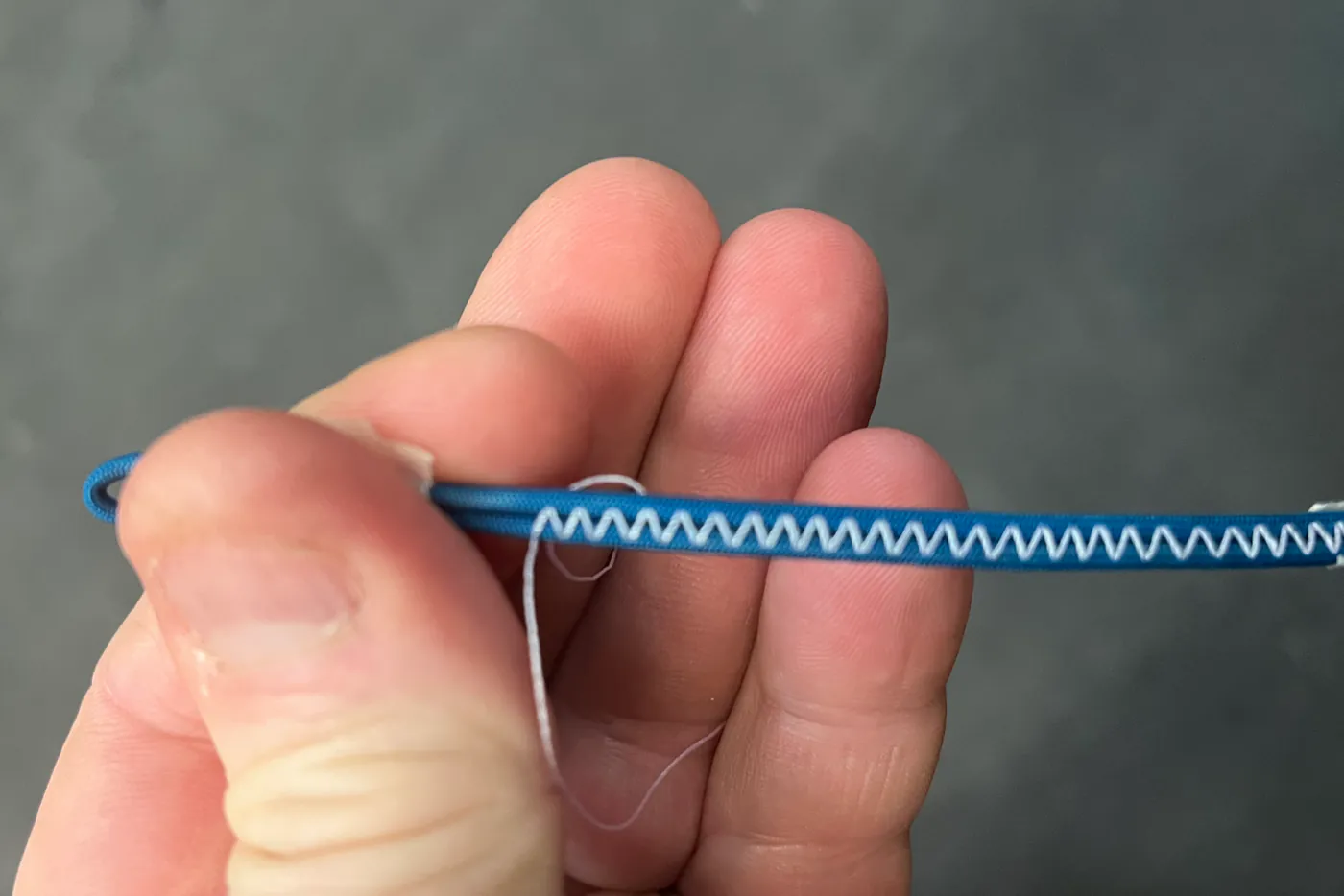 A replacement paraglider line being sewn with a reinforced loop